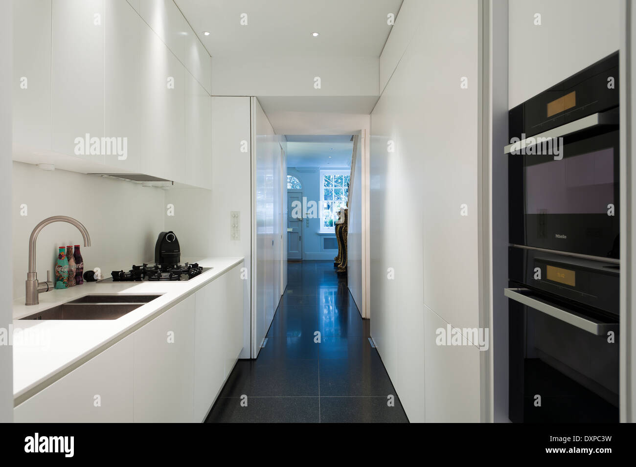 Minima moderna cucina bianca con vista attraverso alla porta anteriore Foto Stock