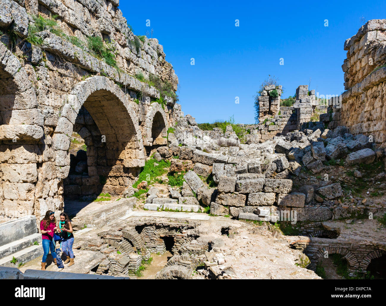 I turisti nelle rovine dei bagni a sud della città antica di Perge, della Panfilia, Provincia di Antalya, Turchia Foto Stock