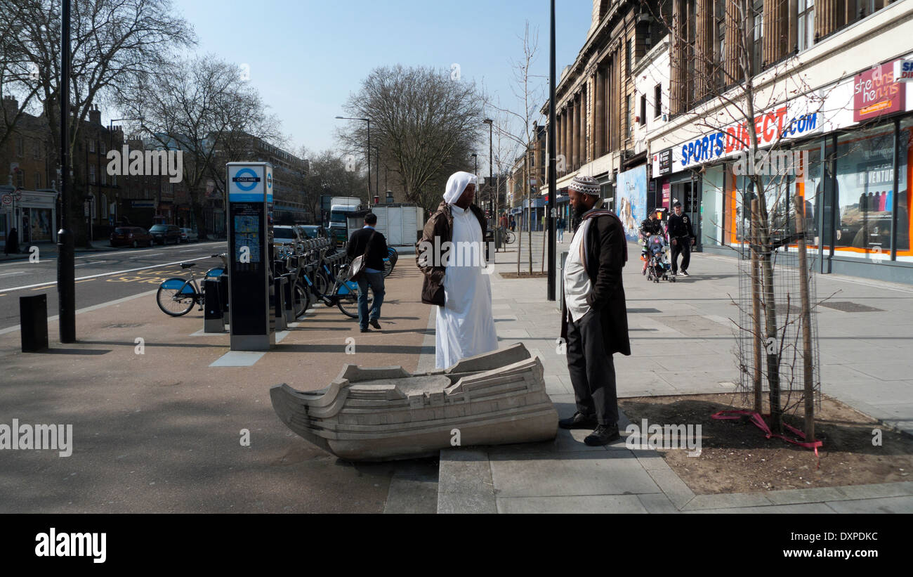Due uomini musulmani nella conversazione accanto alla barca in calcestruzzo su Mile End Road Whitechapel East London, Regno Unito KATHY DEWITT Foto Stock