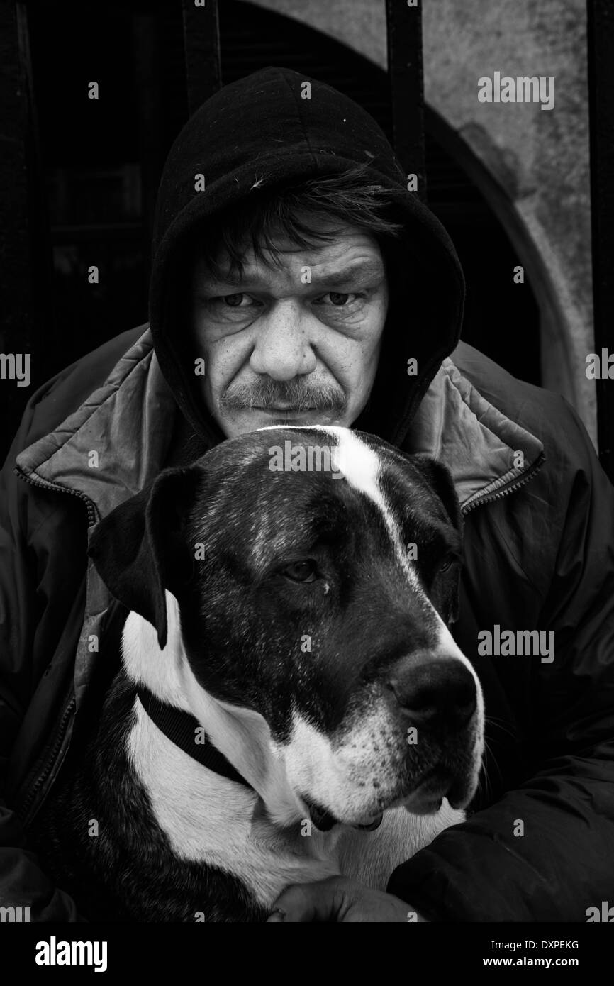 Senzatetto uomo seduto con il suo cane Boxer. Foto Stock