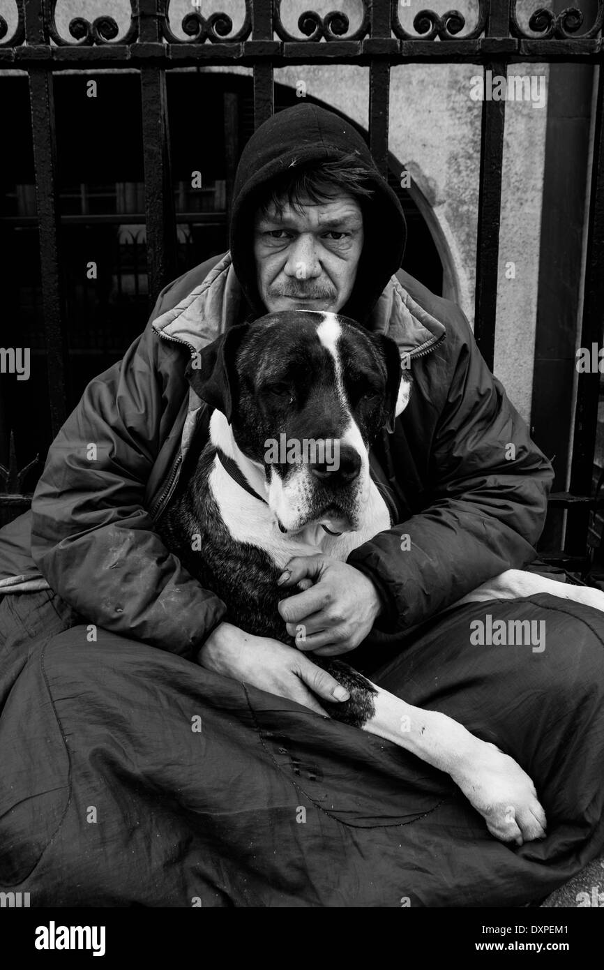 Senzatetto uomo seduto con il suo cane Boxer. Foto Stock