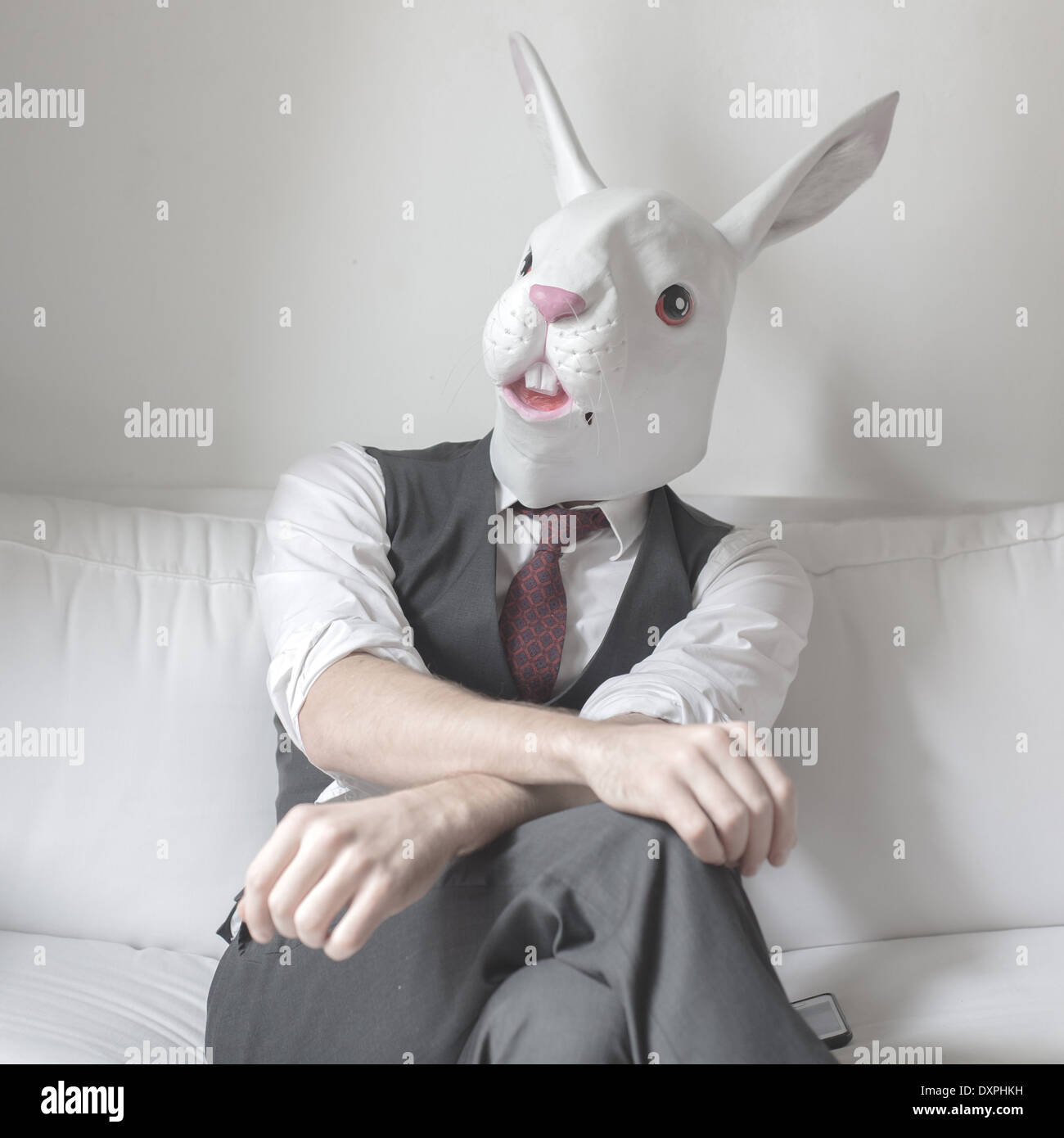 Maschera di coniglio uomo seduto sul divano di casa Foto stock - Alamy