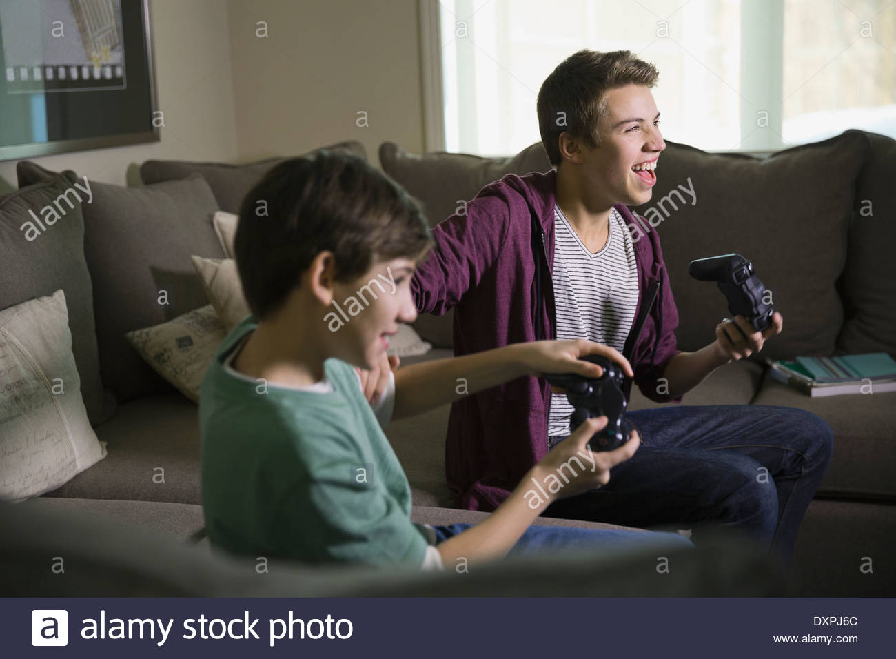 Fratelli eccitati per giocare con i videogiochi su divano Foto Stock