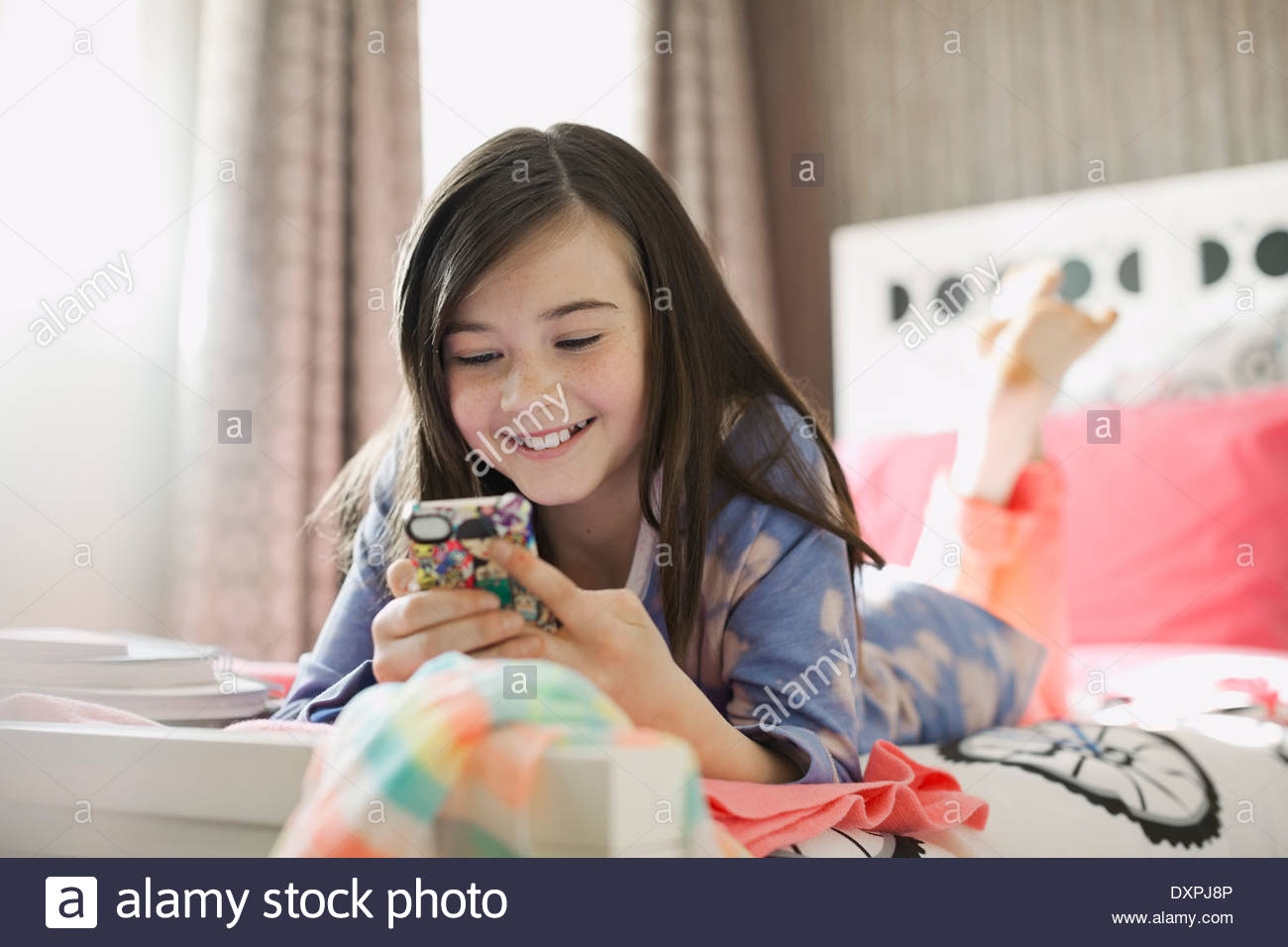 Sorridente ragazza utilizzando smart phone nel letto Foto Stock