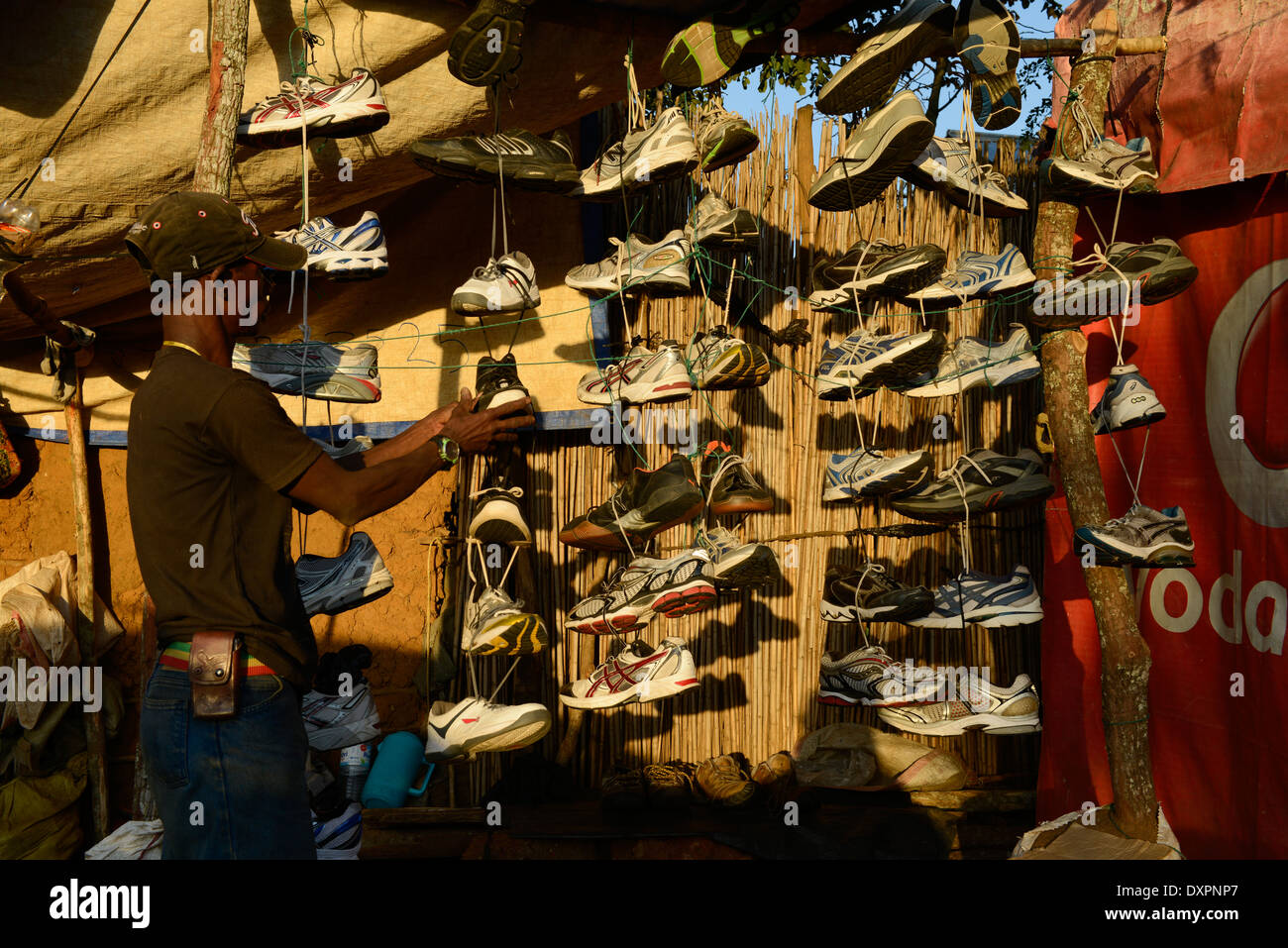 TANZANIA Geita, artigianale miniere d'oro in Mgusu, dove circa 4000 persone vivono e lavorano, principale strada con i negozi, bar e mercato, venditore ambulante vende calzature sportive Foto Stock