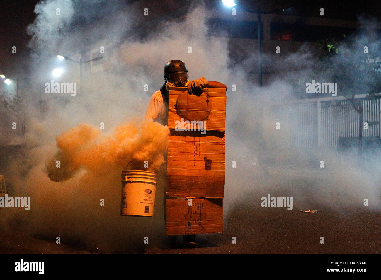 (140329) -- CARACAS, 29 marzo 2014 (Xinhua) -- un dimostratore copre se stesso durante gli scontri con i membri della Nazionale Bolivariano Guard (GNB), a una protesta nel comune di Chacao, a est di Caracas, Venezuela, il 28 marzo 2014. Foto Stock