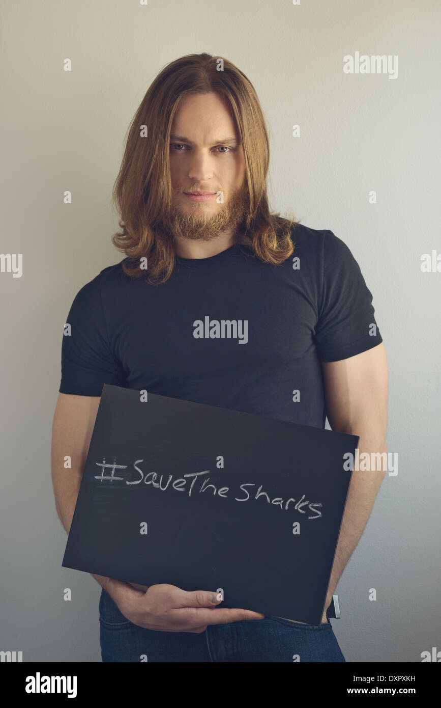 Un uomo con la barba tenendo un cartello per promuovere 'salva squali' Foto Stock