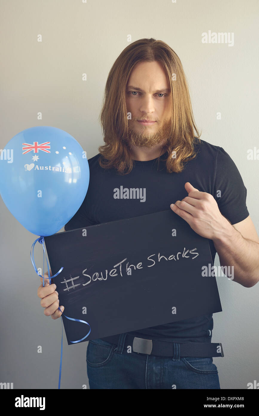 Un uomo con la barba tenendo un cartello per promuovere 'salva squali' e una blu 'I love Australia' palloncino Foto Stock