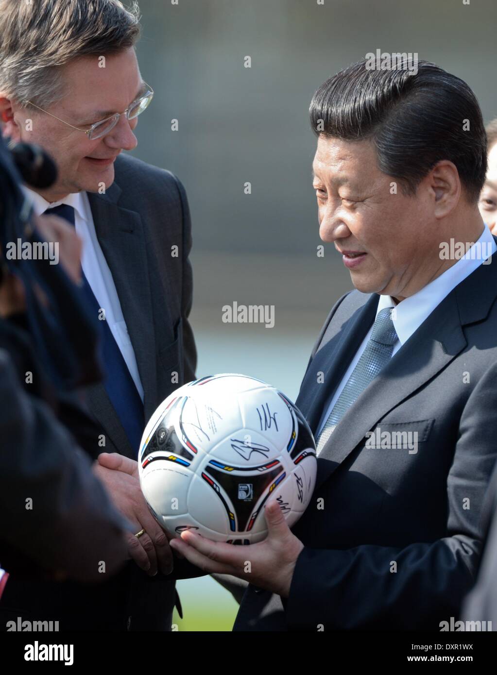 Il presidente cinese e Segretario Generale del Partito Comunista della Cina, Xi jinping (R), riceve una partita di calcio dal tesoriere del tedesco Football Association (DFB), Reinhard Grindel, prima di iniziare un amichevole partita di calcio tra i giovani cinesi di team e una selezione di giovani della Bundesliga club di calcio VFL Wolfsburg con una T-shirt autografata da Wolfsburg la Bundesliga giocatori al Parco Olimpico di Berlino, Germania, 29 marzo 2014. È la prima visita di Stato in Germania da parte di un presidente cinese per otto anni. Il cordiale partita di calcio è stato il culmine di una settimana di calcio clinica per i giovani Foto Stock