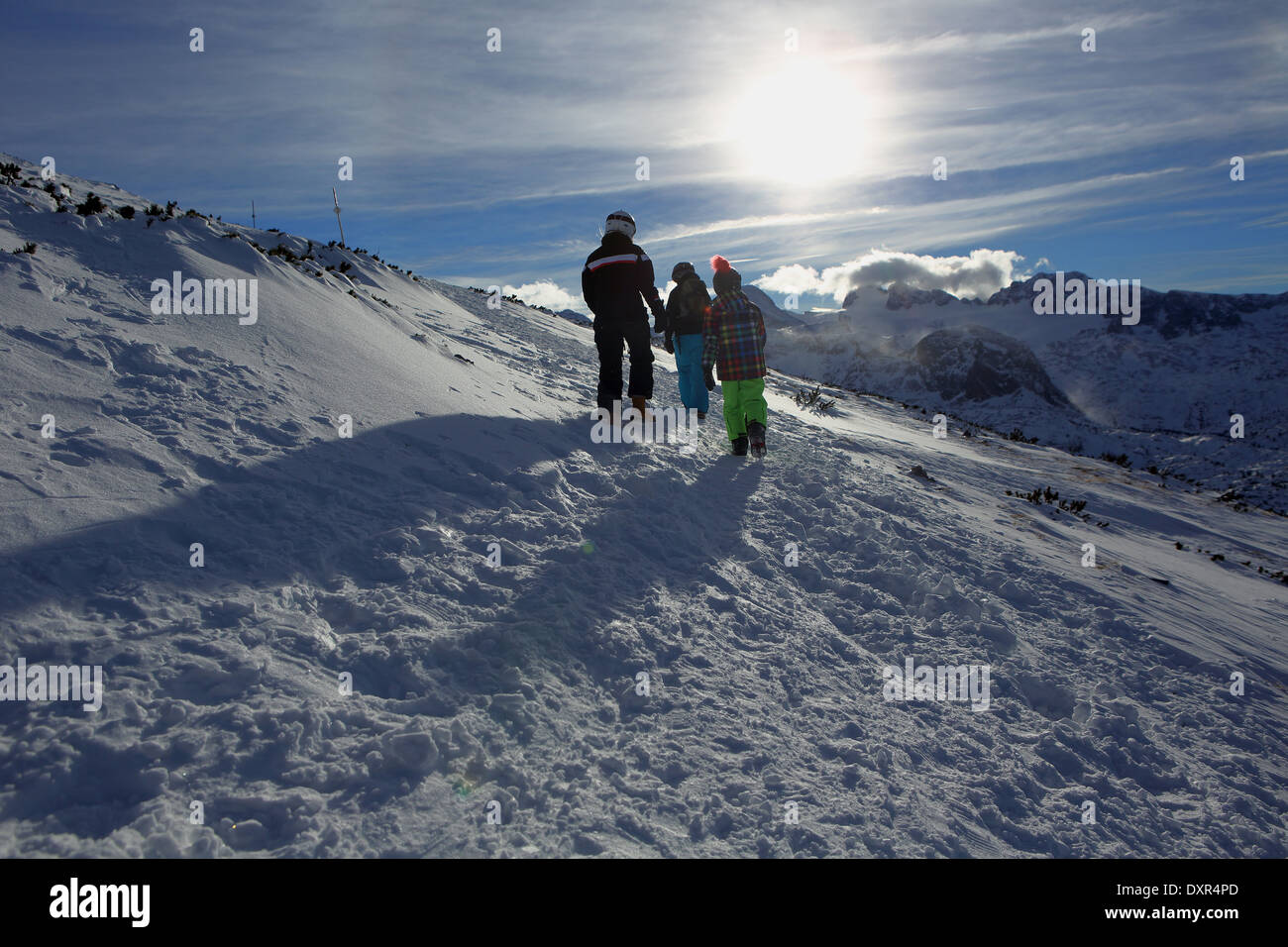 Obertraun, moglie e figli in esecuzione sul versante di una montagna attraverso la neve Foto Stock