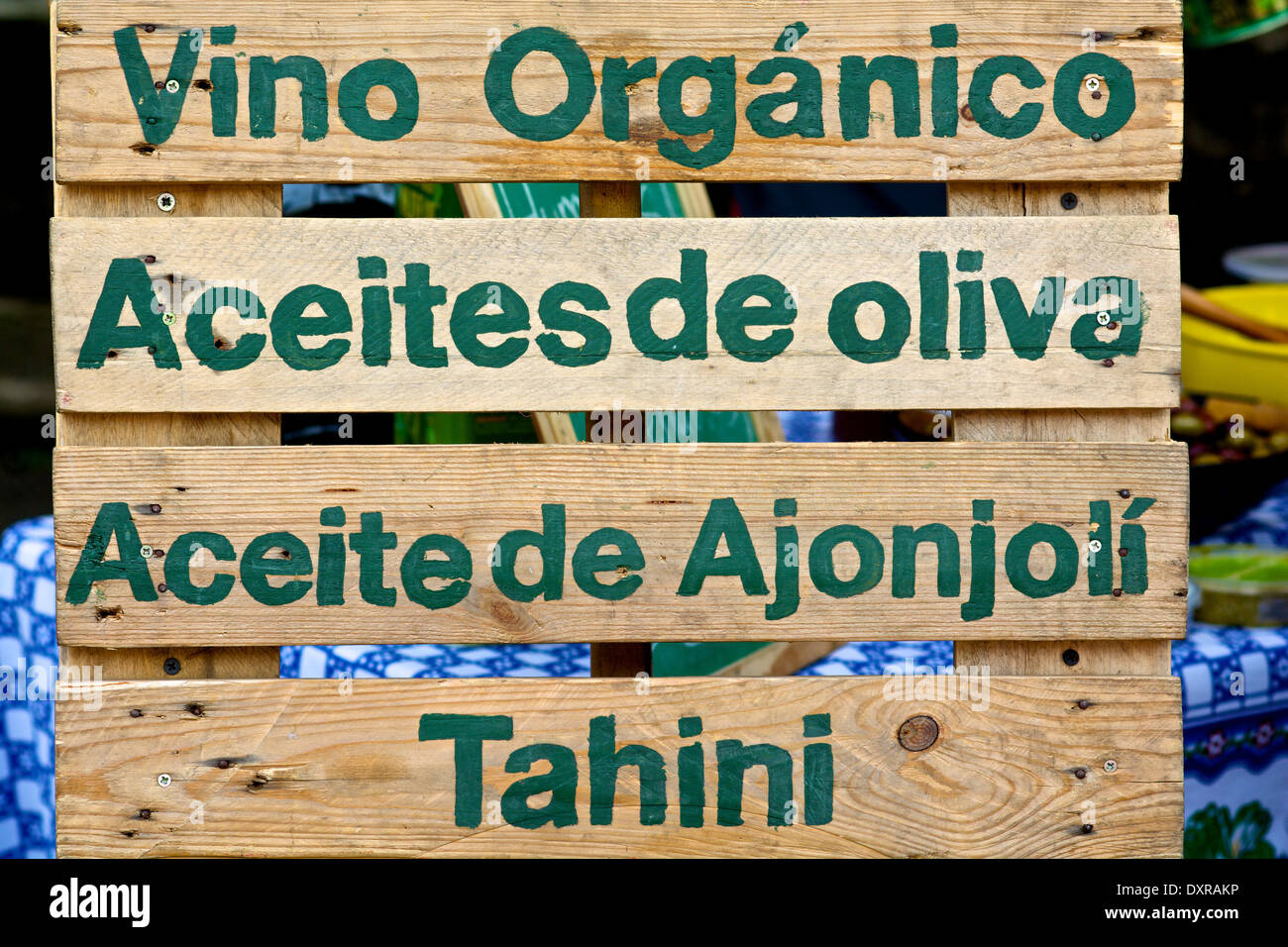 Un cartello in legno con le parole: "vino biologico", "olio di oliva", "olio di esame' e 'tahini' in spagnolo. Foto Stock