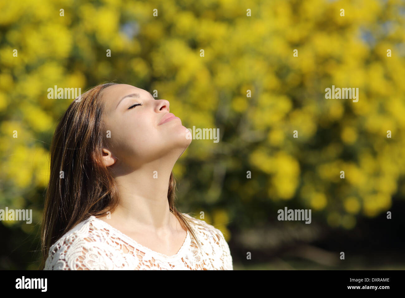 Donna respirazione profonda in primavera o in estate con uno sfondo giallo Foto Stock
