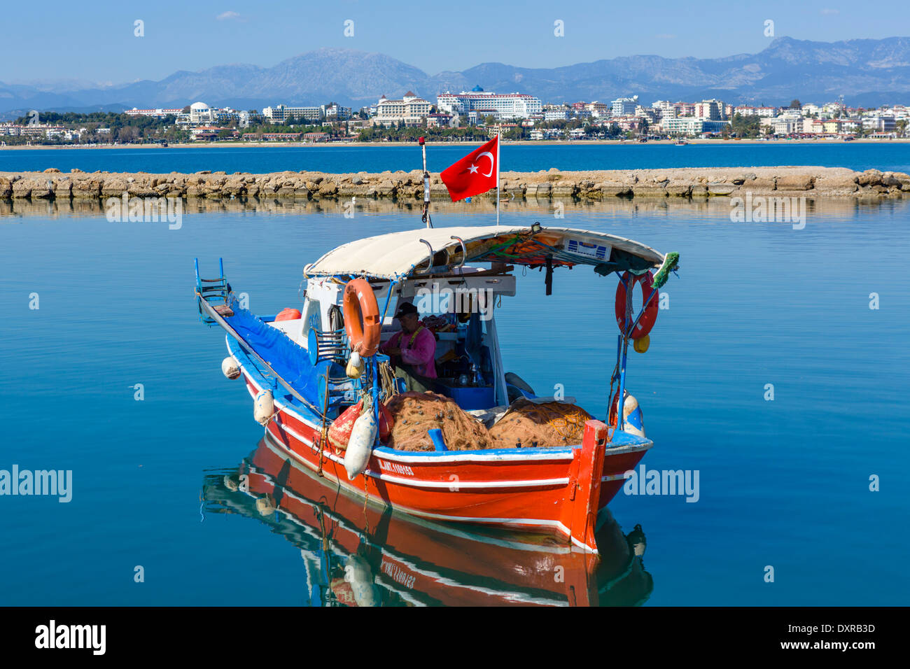 Barca da pesca nella città vecchia porto guardando verso le spiagge e hotel zona ad ovest della città, laterale, Provincia di Antalya, Turchia Foto Stock