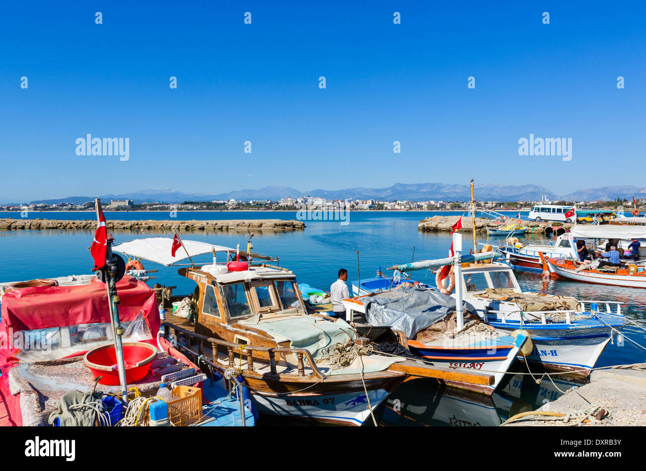 Barche da pesca nella città vecchia porto guardando verso le spiagge e hotel zona ad ovest della città, laterale, Provincia di Antalya, Turchia Foto Stock
