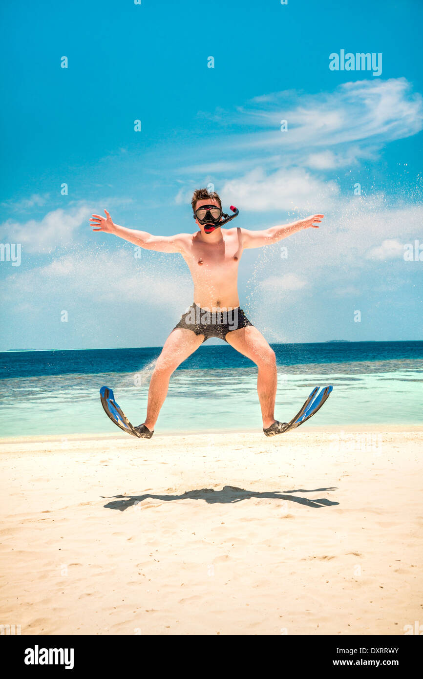 Funny Man jumping in pinne e maschera. Casa vacanze su una spiaggia tropicale a isole delle Maldive. Foto Stock