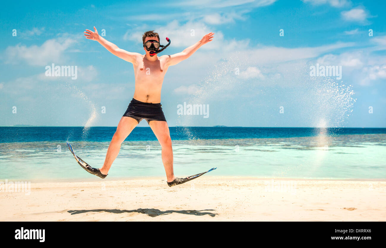 Funny Man jumping in pinne e maschera. Casa vacanze su una spiaggia tropicale a isole delle Maldive. Foto Stock