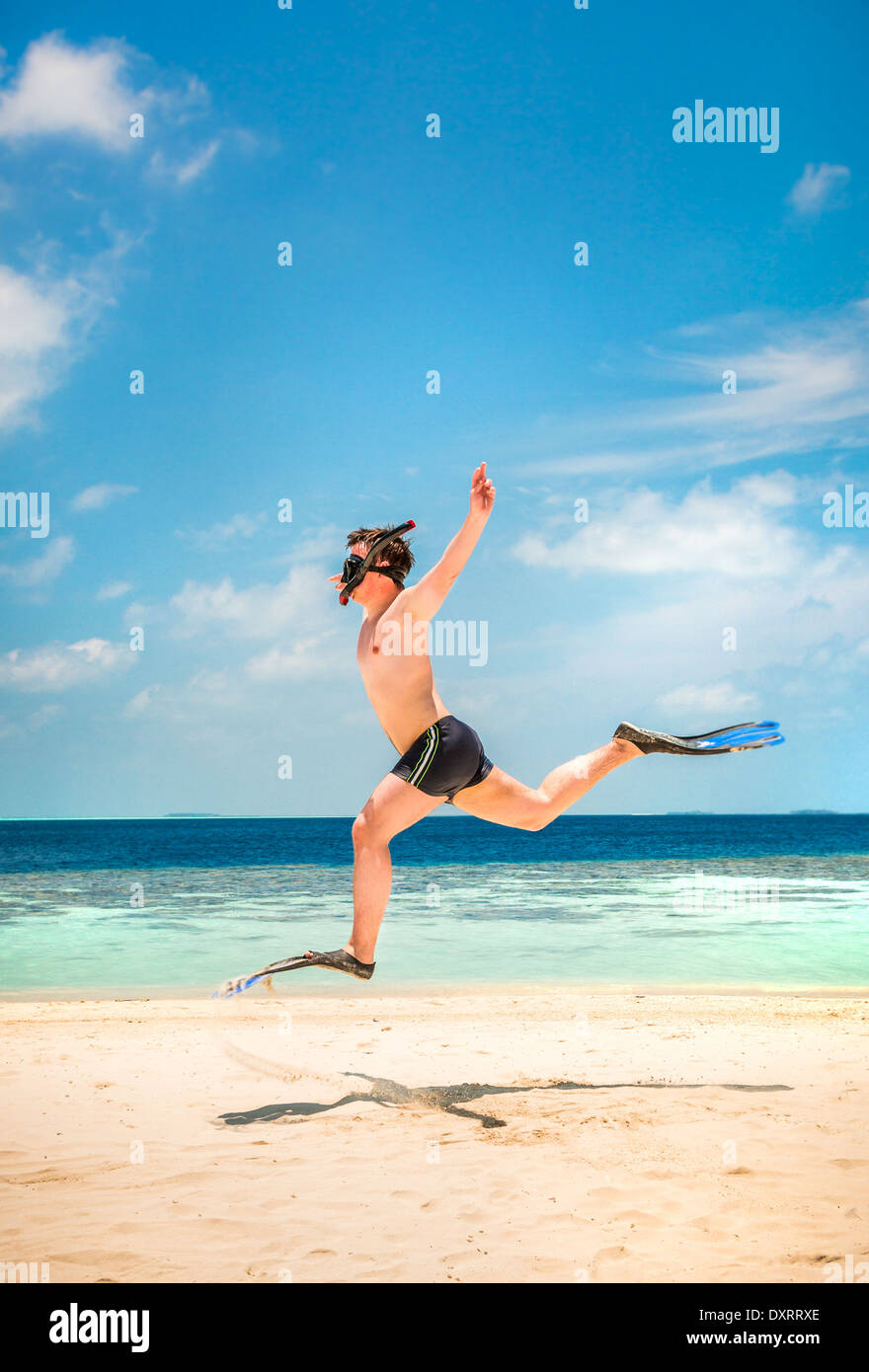 Funny Man jumping in pinne e maschera. Casa vacanze su una spiaggia tropicale a isole delle Maldive. Foto Stock