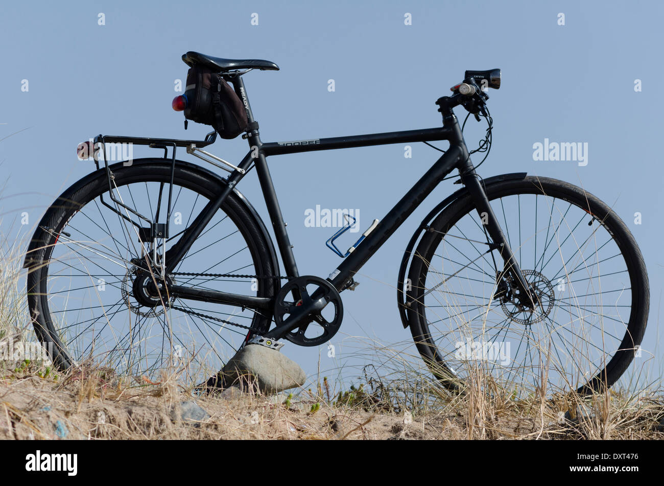 Una bici nero in piedi sulle dune vicino a Seascale contro un luminoso marzo cielo blu. Foto Stock