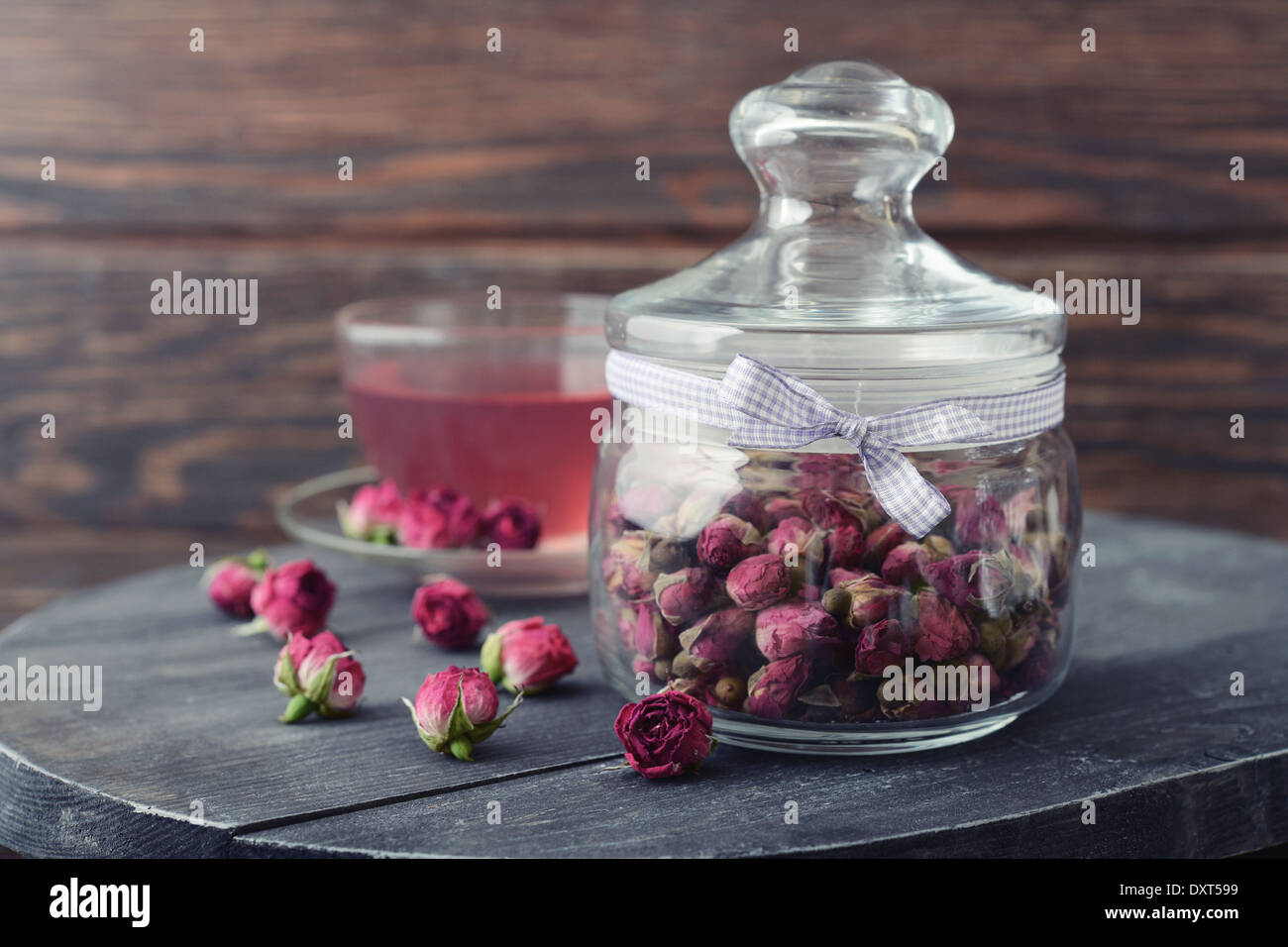 Tea rose fiori in vaso di vetro e tè su sfondo di legno Foto Stock