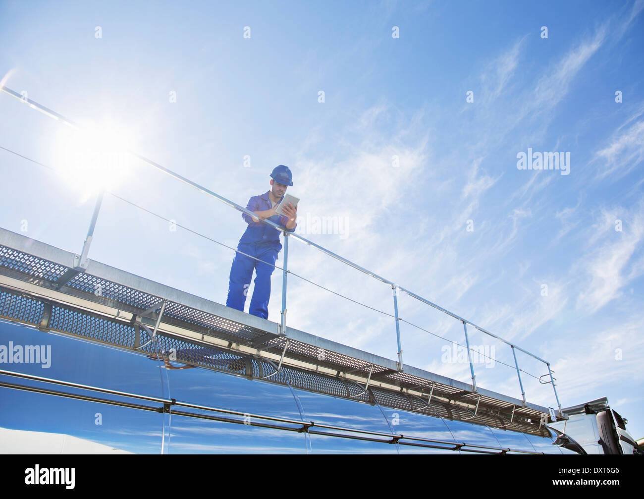 Lavoratore con tavoletta digitale permanente sulla piattaforma sopra di acciaio inox autocisterna per il latte Foto Stock