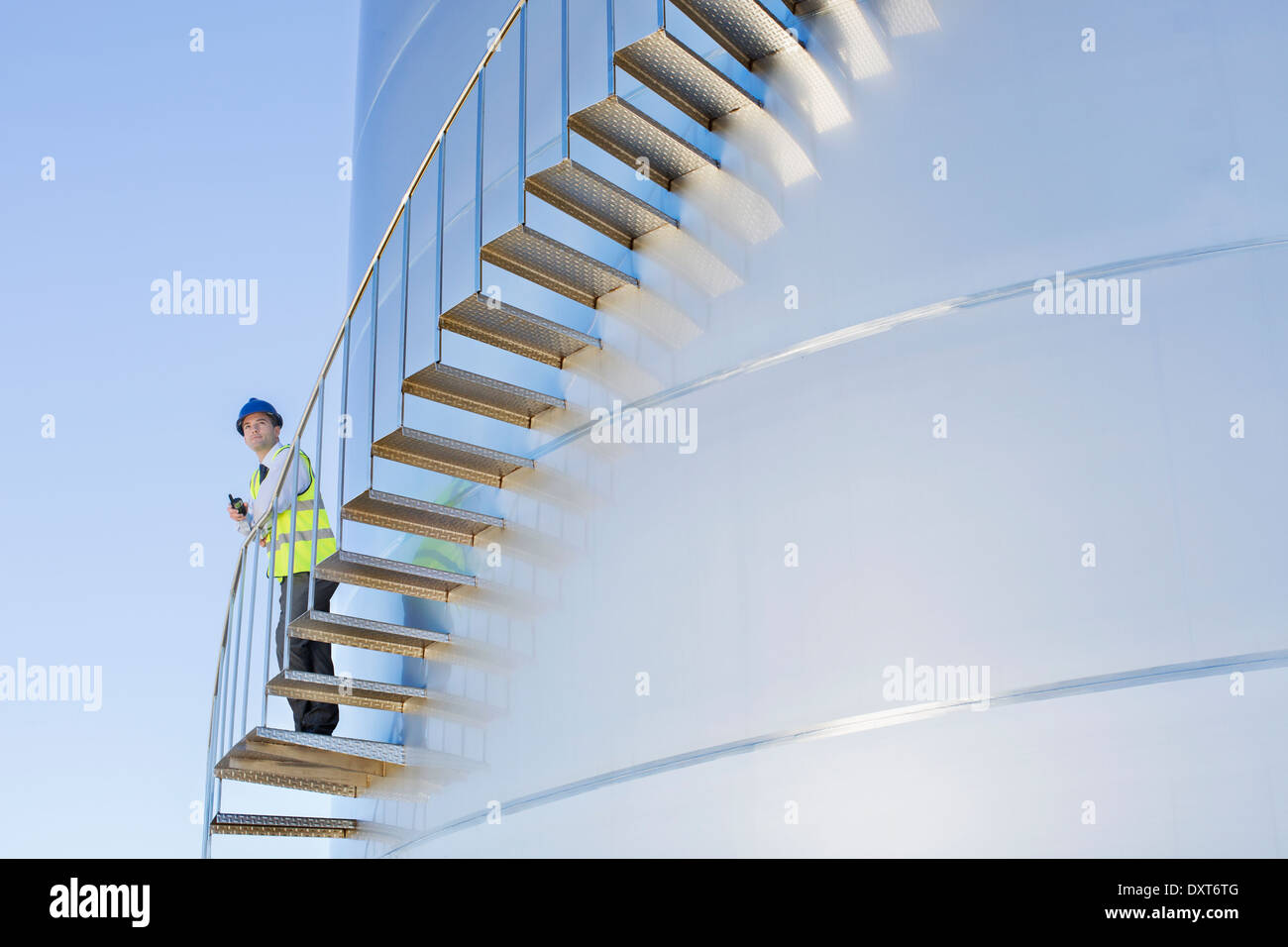 Lavoratore con un walkie-talkie in piedi sulle scale che si snoda lungo insilato torre di storage Foto Stock