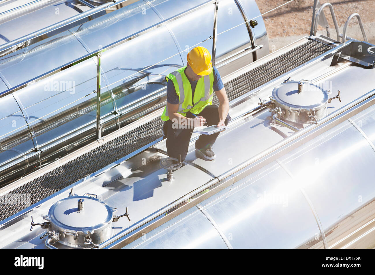 Lavoratore con tavoletta digitale sulla parte superiore di acciaio inox autocisterna per il latte Foto Stock