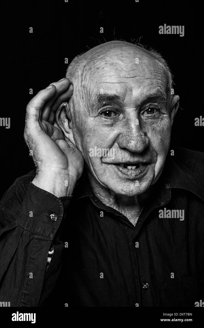 Il vecchio uomo che sente male, mano all'orecchio ascolta isolato su sfondo nero Foto Stock