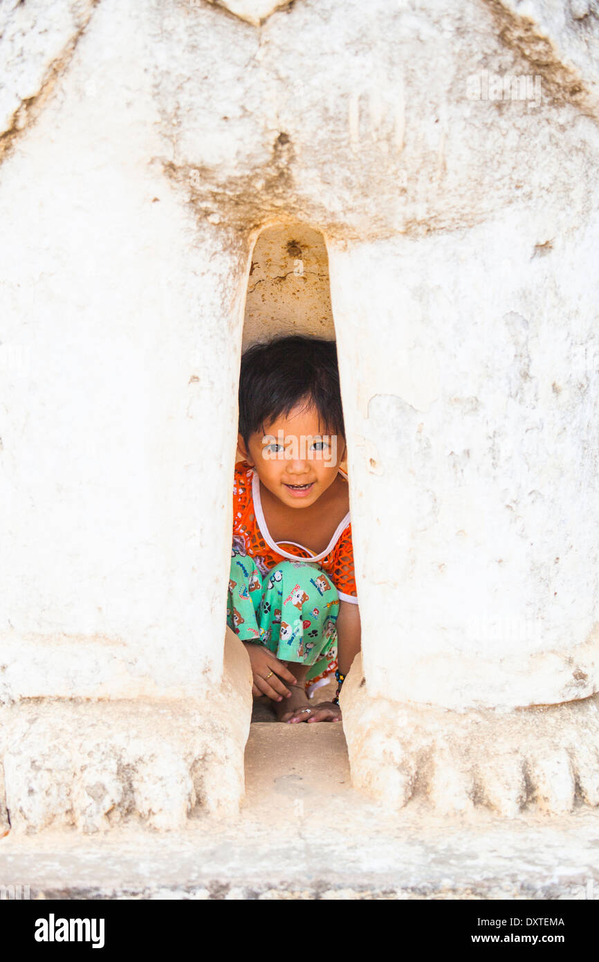 Giovane ragazza birmano all'interno delle gambe di una statua di Bagan, Myanmar Foto Stock