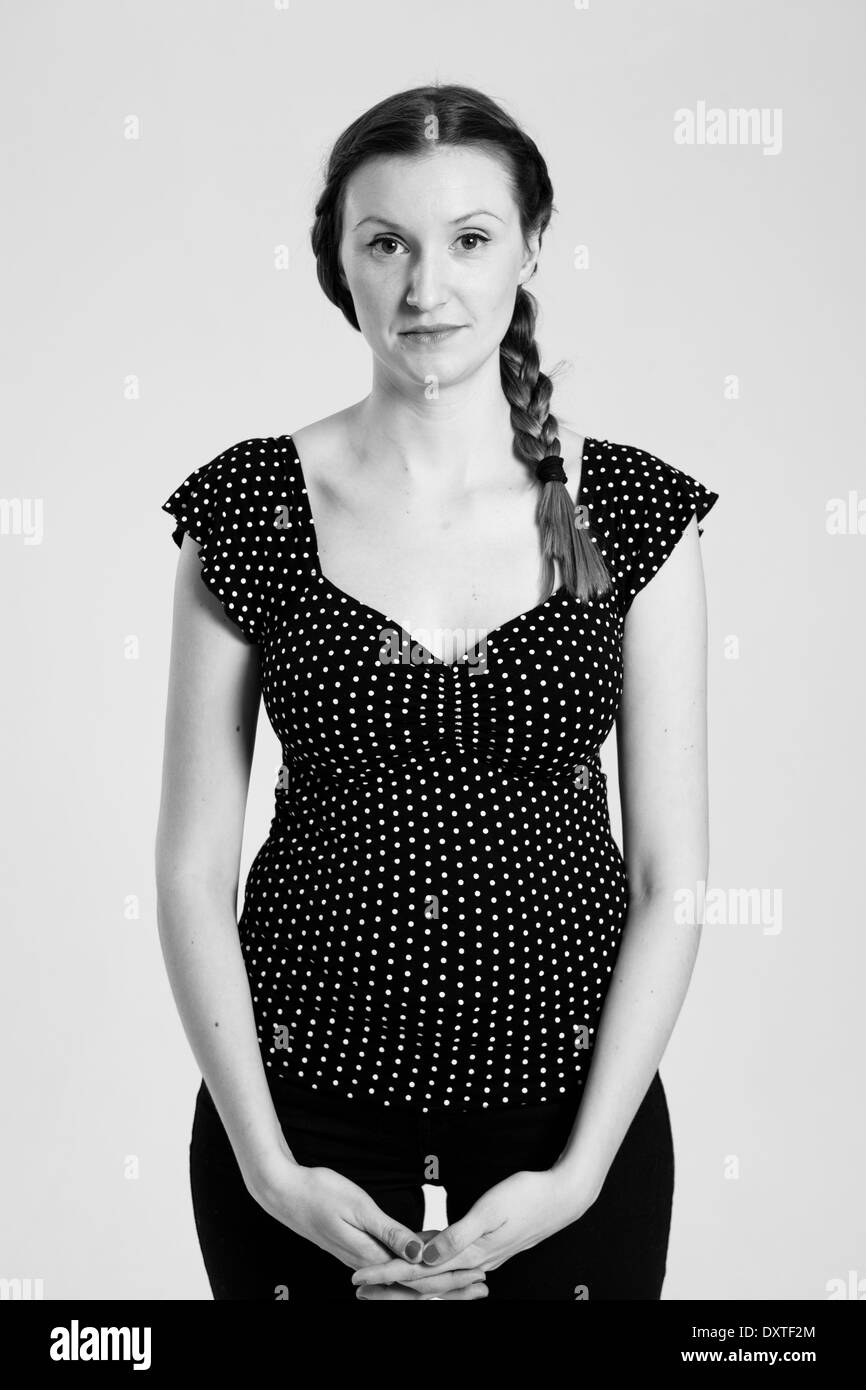 Bianco e nero studio ritratto di donna attraente con spiralina tenendo le mani insieme Foto Stock