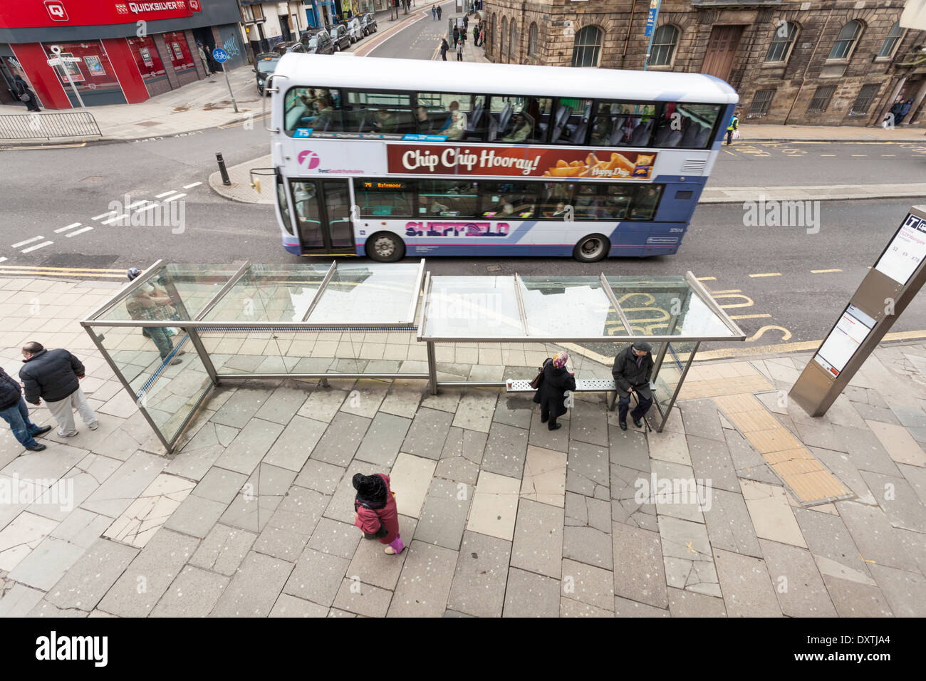Guardando verso il basso su una città del Regno Unito street e fermata bus con persone in attesa e un autobus a due piani passanti. Sheffield, nello Yorkshire, Inghilterra, Regno Unito Foto Stock