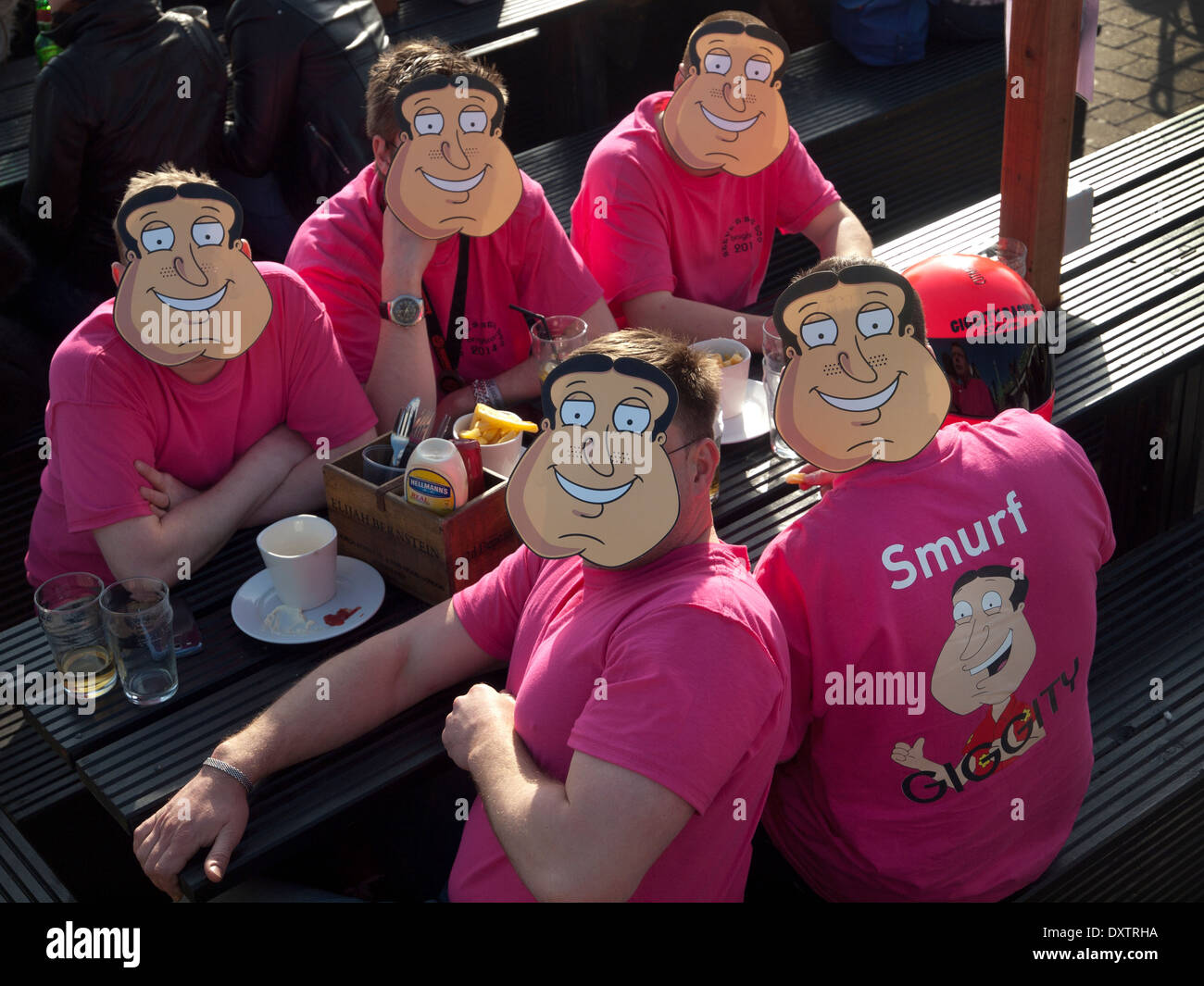 Un gruppo di uomini in Brighton Seafront bar per un addio al celibato, indossare le maschere del Pantano, da un personaggio della serie TV Family Guy Foto Stock
