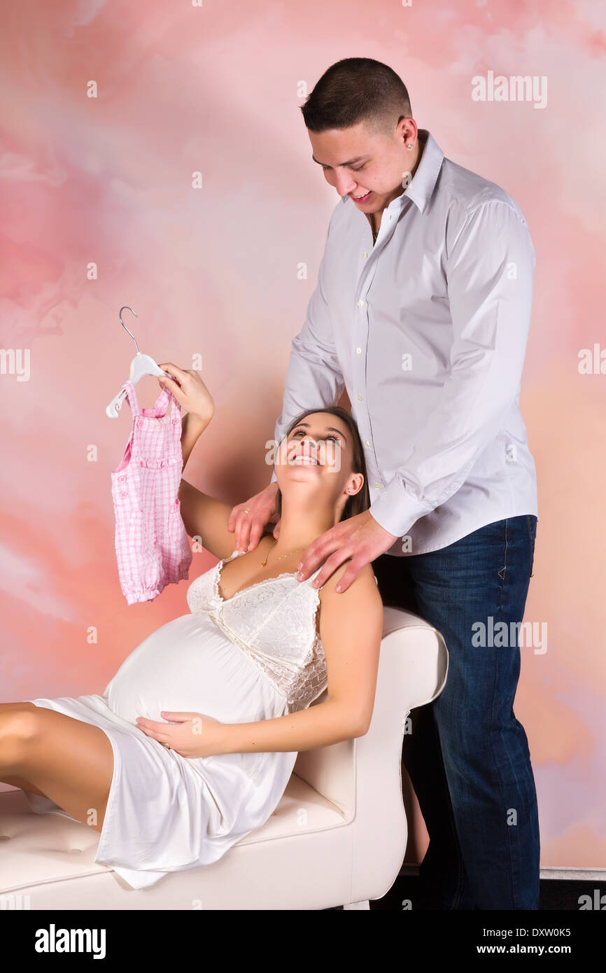 Felice giovane donna incinta che mostra i nuovi vestiti del bambino Foto Stock
