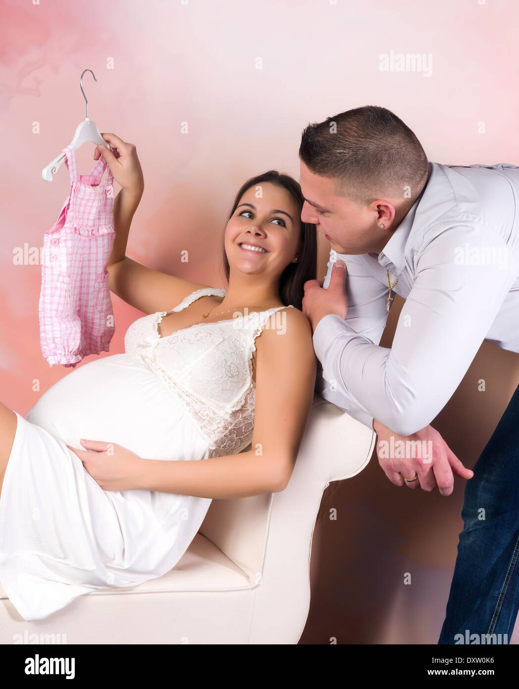 Felice giovane donna incinta che mostra i nuovi vestiti del bambino Foto Stock