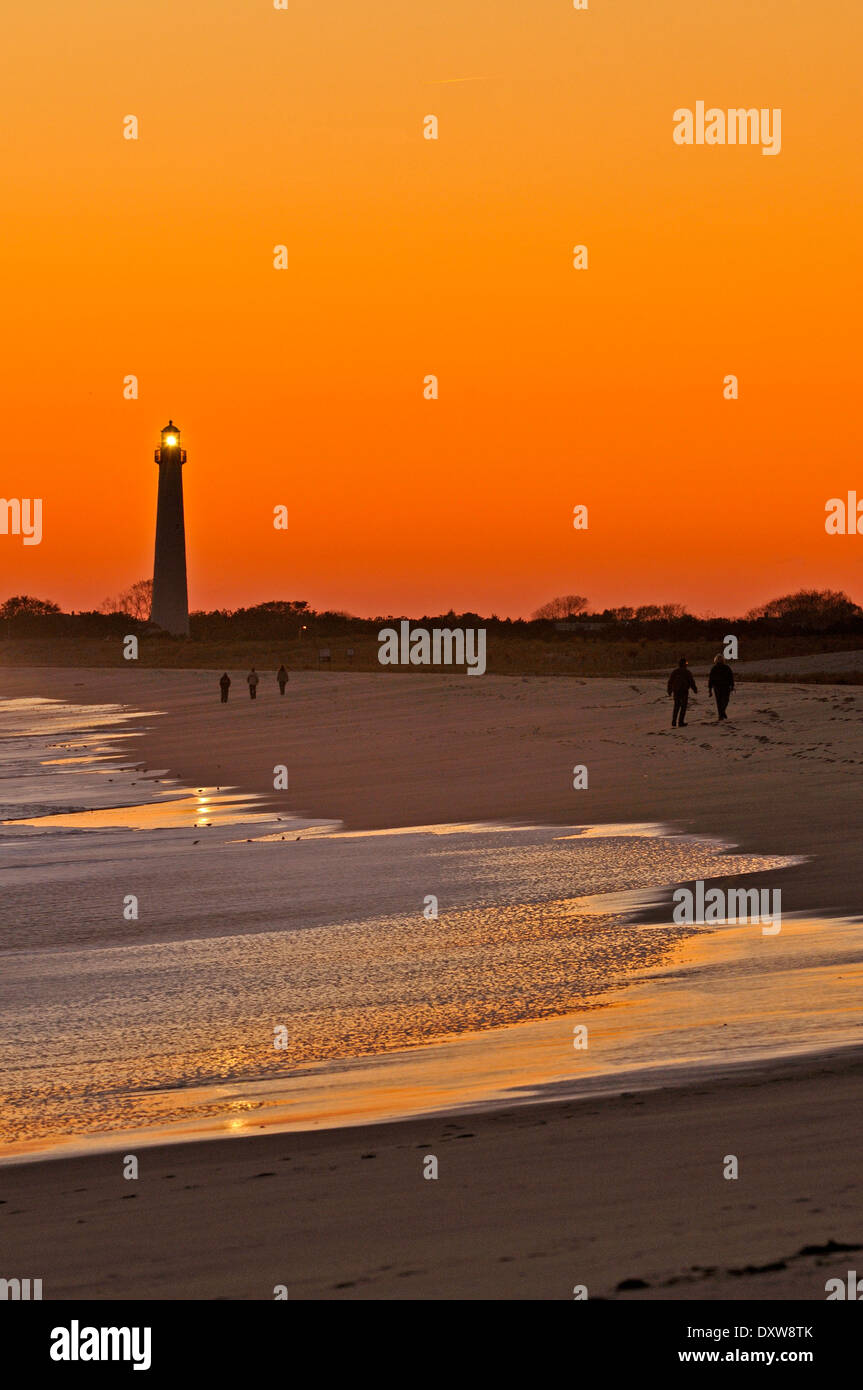 La gente camminare sulla spiaggia al tramonto a Cape May, New Jersey, Stati Uniti d'America con il Cape May Point Lighthouse in background. Foto Stock