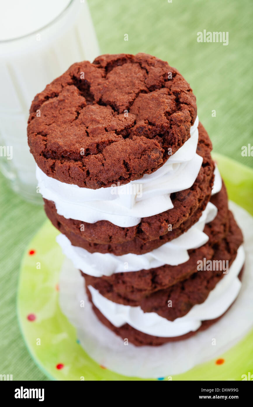 Una pila di crema cioccolato ripieno di cookie e un bicchiere di latte freddo. Foto Stock