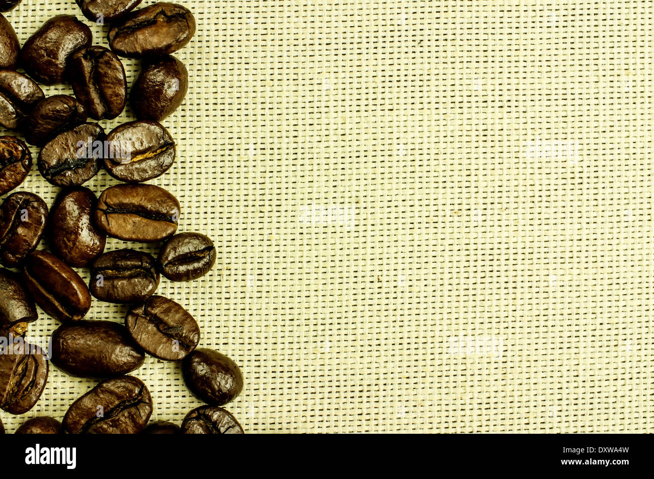 Freschi chicchi di caffè tostati close-up nella barra sulla sinistra. Lo sfondo naturale di tessuto. Foto Stock