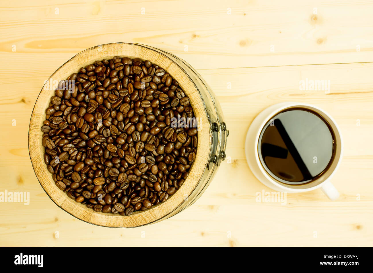I chicchi di caffè in un barile di legno. Nei pressi di un grande bianco tazza di caffè. Foto Stock