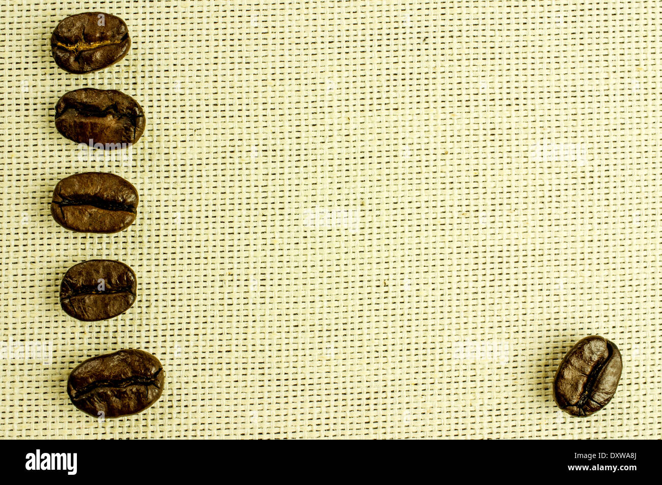 Freschi chicchi di caffè tostati close-up in una linea verticale. Lo sfondo naturale di tessuto. Foto Stock