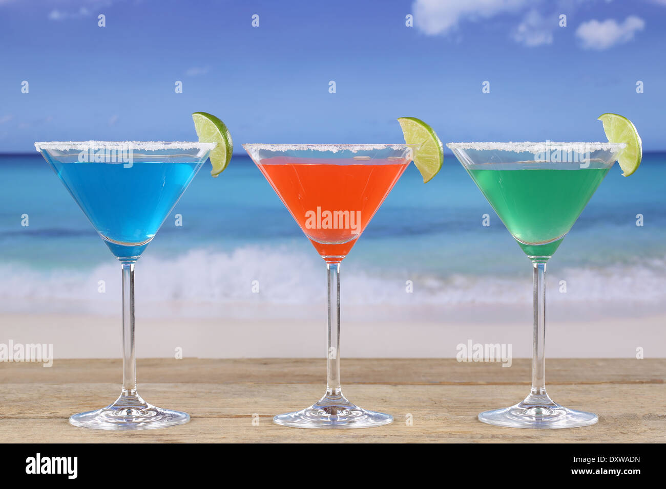 Cocktail colorati in bicchieri da Martini sulla spiaggia mentre è in vacanza Foto Stock