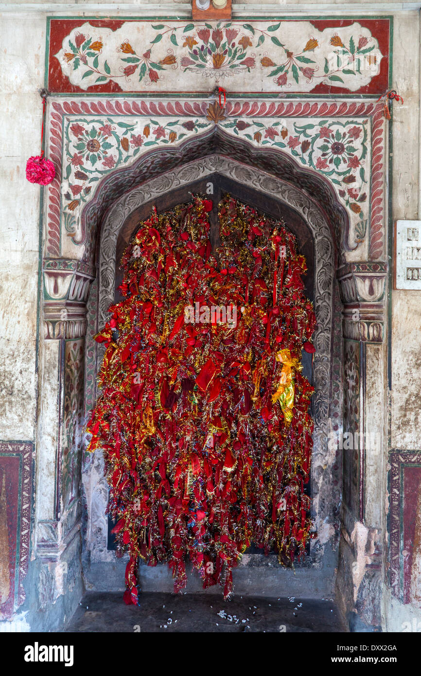 India, Dehradun. Visitatori tie bit di panno rosso alla finestra della struttura a reticolo come un simbolo di preghiere offerte a un tempio sikh. Foto Stock