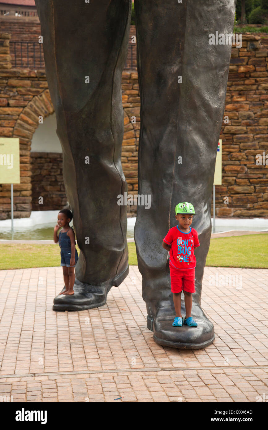 Bambini ai piedi del grande Nelson Mandela statua che si trova nella parte anteriore dell'Unione edifici edifici governativi, Pretoria Gauteng Foto Stock
