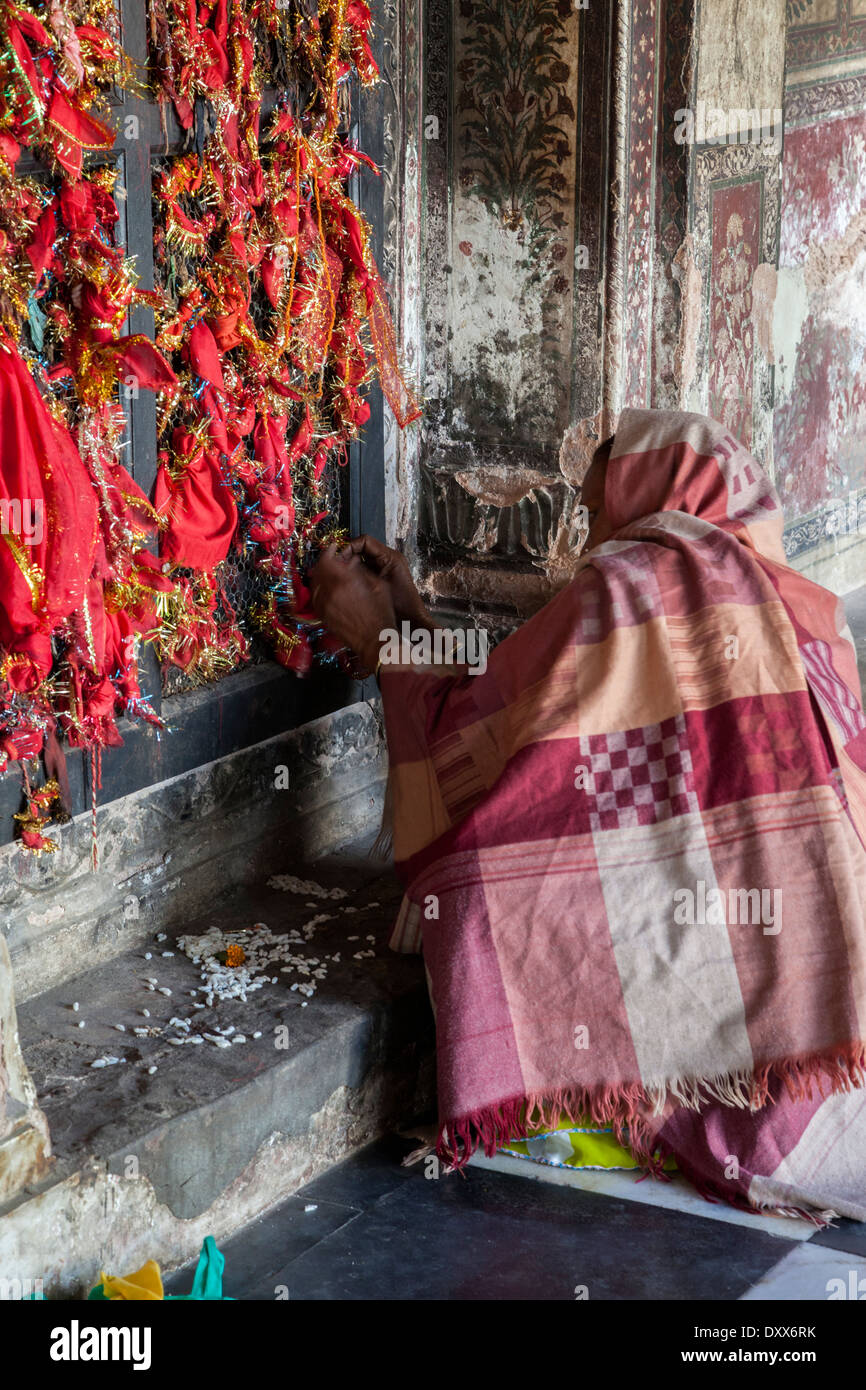 India, Dehradun. Un visitatore cravatte bit di panno rosso alla finestra della struttura a reticolo come un simbolo di preghiere offerte a un tempio sikh. Foto Stock