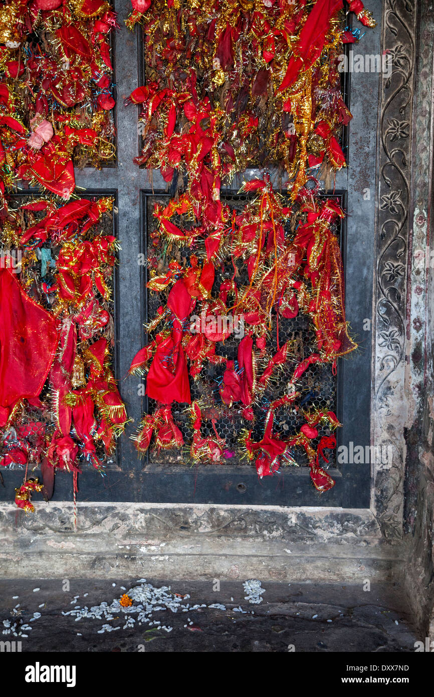 India, Dehradun. Visitatori tie bit di panno rosso alla finestra della struttura a reticolo come un simbolo di preghiere offerte a un tempio sikh. Foto Stock