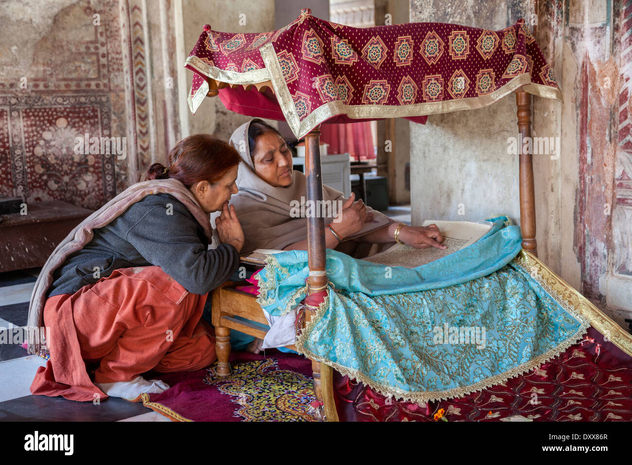 India, Dehradun. Donna lettura della Sacra Scrittura per adoratori in un tempio sikh costruito nel 1707. Foto Stock