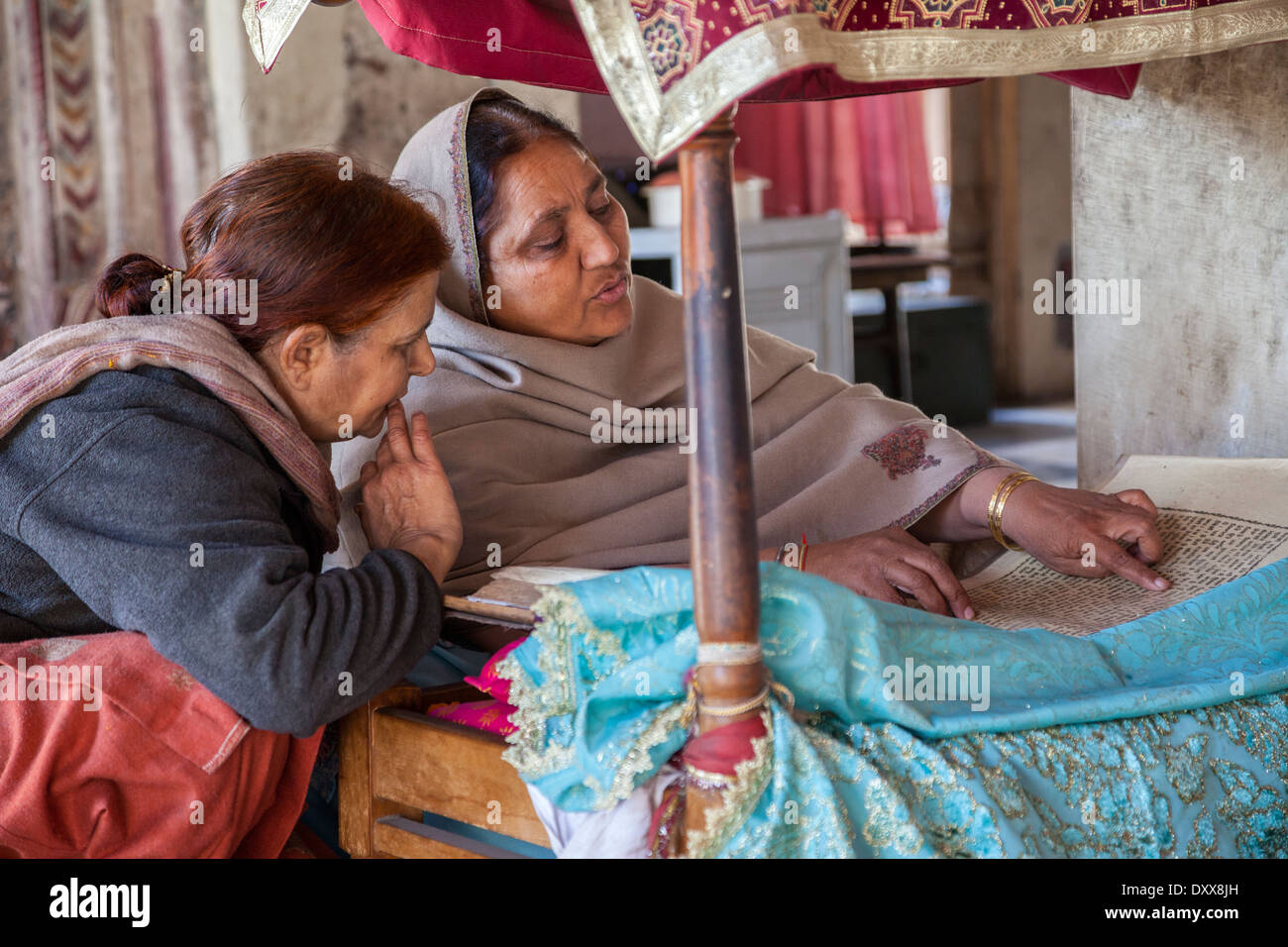India, Dehradun. Donna lettura della Sacra Scrittura per adoratori in un tempio sikh costruito nel 1707. Foto Stock