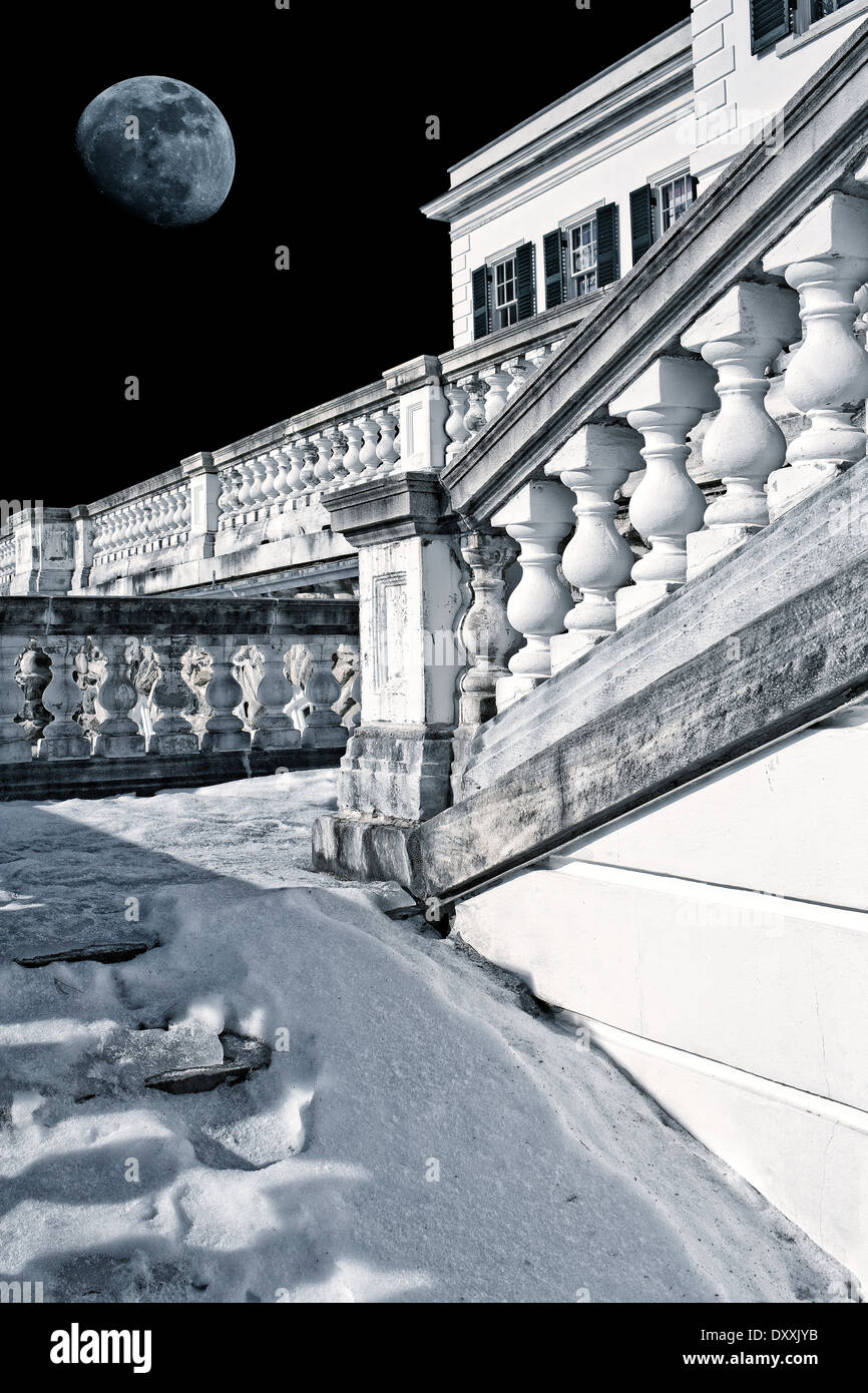 Coperta di neve scale che conducono fino a una età dorata mansion sotto una luna piena. Foto Stock