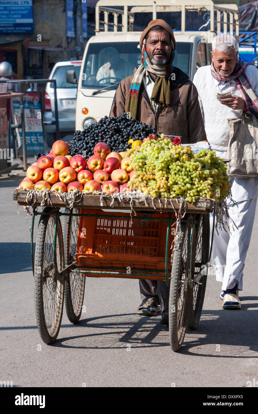 India, Dehradun. Fornitore di frutta e il suo carrello in strada. Foto Stock