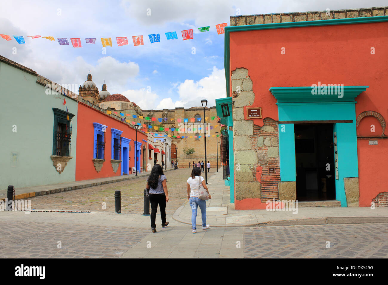 Due persone che camminano giù per una strada di ciottoli rivestiti con i suoi edifici colorati a Oaxaca, Messico Foto Stock