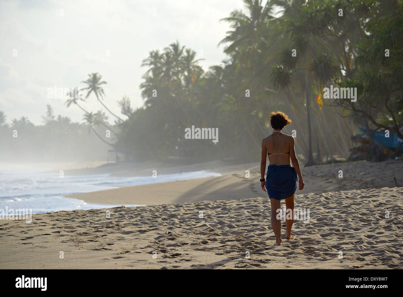 Donna che cammina sulla spiaggia tropicale al tramonto, Tangalla, Sri Lanka. Foto Stock