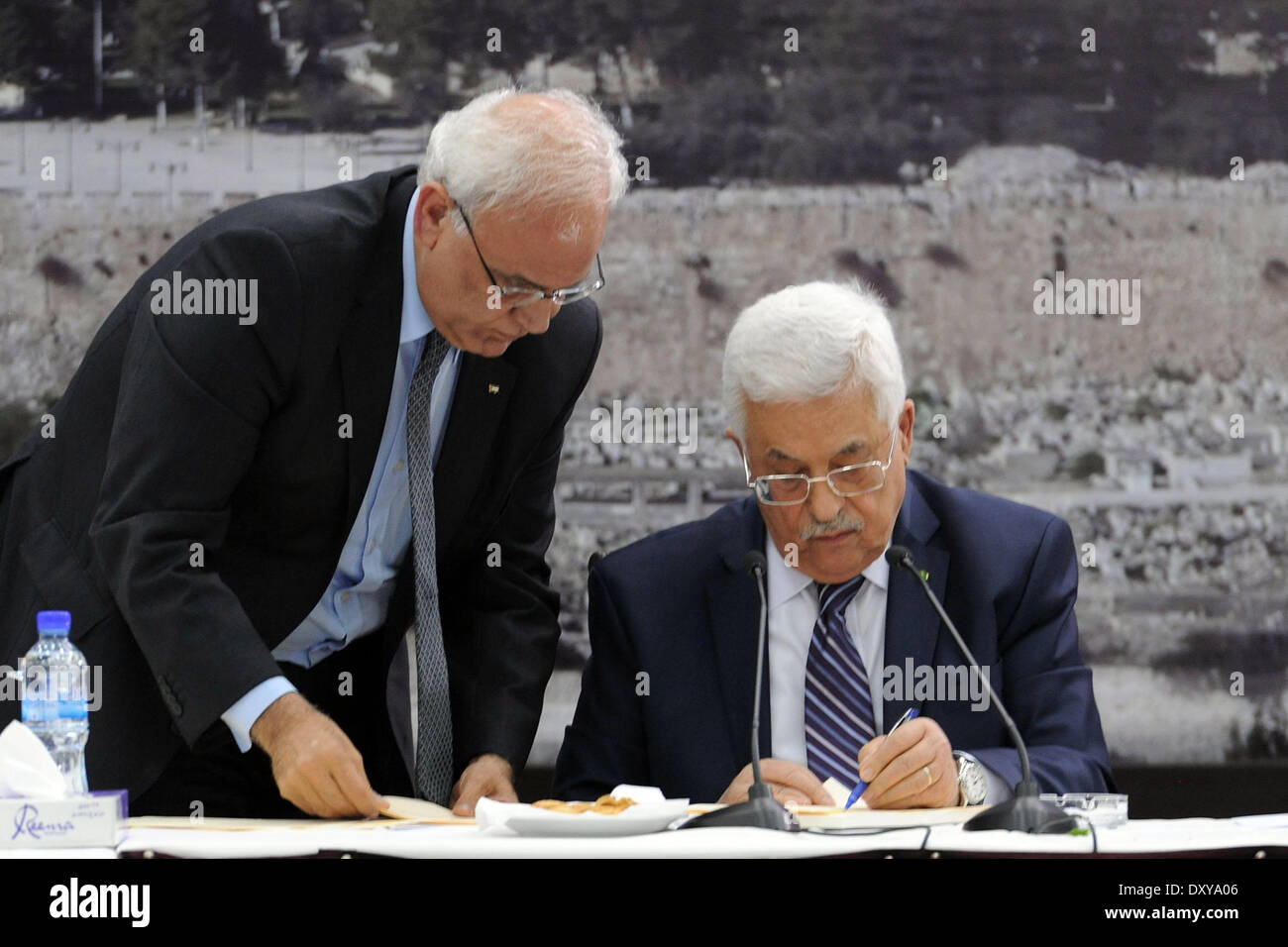 Ramallah. 1 apr, 2014. Il presidente palestinese Mahmoud Abbas (R) i segni di una richiesta sulla congiungente 15 agenzie delle Nazioni Unite e i trattati internazionali nel corso di un incontro con i leader palestinesi presso il suo ufficio in Cisgiordania città di Ramallah il 1 aprile 2014. Abbas ha firmato una richiesta di martedì a unirsi a 15 agenzie delle Nazioni Unite e dai trattati internazionali in risposta a Israele di ritardo per rilasciare il gruppo finale di palestinesi a lungo termine detenuti. Credito: Piscina/Xinhua/Alamy Live News Foto Stock